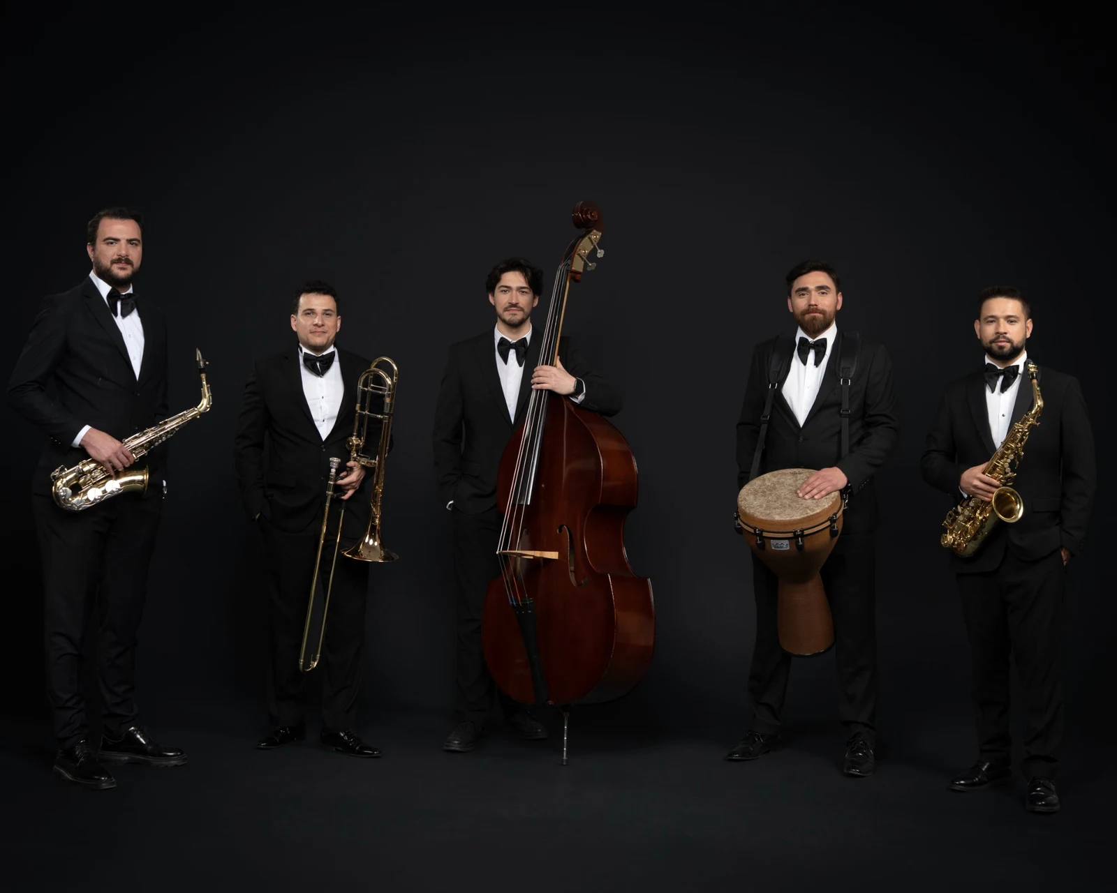 Smokinli beş müzisyen The Gentlemen: saksafonlar, trombon, kontrbas ve djembe
